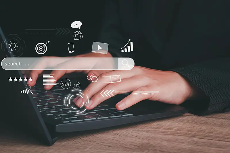 Hands typing on a laptop using a search engine