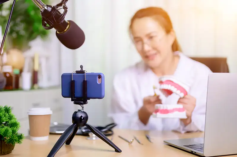 Dentist recording educational dental video with phone