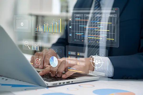 Hands typing on a laptop with charts and graphs